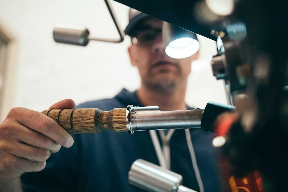 Close-up of a machinist working a metal part at a machining station under a task light