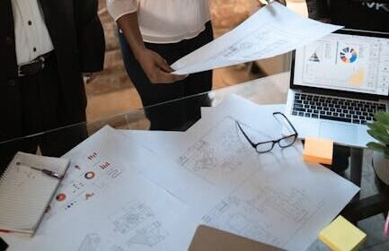 A diverse business team reviews printed plans in a modern office setting.
